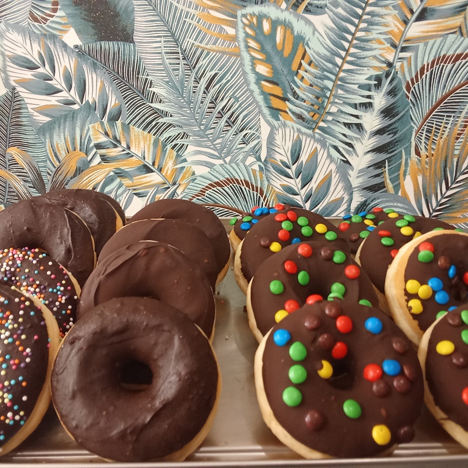 Donuts au chocolat et décorations Festi Douceurs sur plateau à Villefranche-de-Lauragais, ambiance tropicale joyeuse,